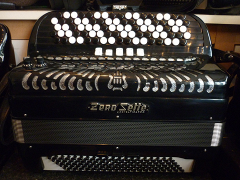 Accordeon ZeroSette Trois voix cent vingt basses Zero Sette nous offre un catalogue impressionnant d’instruments de toute première qualité, tant pour les amateurs éclairés que pour les professionnels. Le son authentique depuis 1945. La marque est reconnue dés sa création en 1945, et conquière immédiatement les marchés Européens, les USA, l’Asie et l’Australie. Idéal pour l’étude, voire le jeu professionnel, cet accordéon Zero Sette possède trois voix au chant, composées de deux flutes, et un basson. Il ne possède pas de boite de résonance, ce qui le rend plus léger. malgré cette absence, la voix basson sonne très profondément, avec un contenu harmonique des plus séduisant. Les sommiers sont d’excellente qualité, bien taillés, et offrant une très large plage dynamique. Les anches sont de type main, montées à la cire, les peaux d’anches sont en cuir. Le clavier chant type international est équipé de boutons larges. Ceci permet un jeu plus fluide. Agrémenté de cinq rangs de boutons, il offre quarante six notes de Mi à DO# sur deux rangs de soupapes. Nous avons ici un accordéon de type caisse piano, un peu plus haut et nettement moins large. Ceci améliore la position de jeu, et modifie le timbre de l’instrument. du reste, il semble plus léger. Il possède cinq registres devant le clavier, aisément accessibles. Côté main gauche. Cent vingt basses occupent un clavier de type 2/4, avec deux rangs de basses, et quatre rangées aux accords, sont inclus les accords diminués si propices aux accords de passage en cas de modulation. Cinq voix de basses offrent un beaux spectre sonore, la note la plus grave est un LA. Il est doté de deux registres sur trois sélecteurs. Ceci offre cinq voix, ou trois. Cet instrument sera accordé selon votre désir, toutefois, il est préférable de lui garder une vibration modérée, voire très lente, genre swing. Il est idéal pour pratiquer un son »jazz ». A noter l’apparence particulièrement propre, de cet accordéon, comme neuf. Tous les  accordéons vendus par Accord Deléon sont pourvus d’un jeu de bretelles housse ou étui  neufs. Assortis d’un service après vente offrant garantie et qualité.