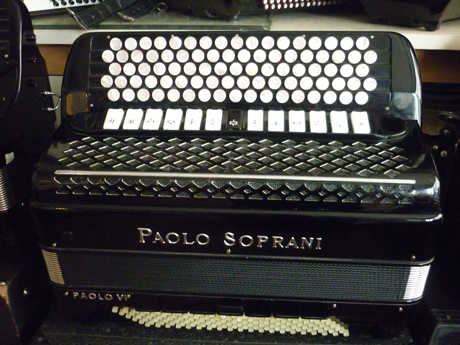 Accordeon Paolo Soprani quatre voix piccolo cent vingt basses Voici une superbe réalisation des ouvriers de chez Paolo Soprani. Ce modèle est extrêmement rare dans sa palette sonore, comme dans sa réalisation. Les matériaux le constituant sont de toute première qualité, l’assemblage est à l’avenant, moyennant quoi il chante dans toutes les nuances du spectre. Haut et fort. Les caisses sont de type piano, quarante huit centimètres par vingt, sur deux rangées de soupapes. La tessiture main droite est de quarante six notes de Mi à DO#, sur quatre voix, 16 8 8 4, basson deux flutes piccolo. Il comporte treize registres devant un clavier de type international sur cinq rangs, pour une largeur de voie de vingt millimètres. La table d’harmonie ne comporte pas de boite de résonance, ce qui en facilite l’amplification. Cet accordéon de qualité professionnelle affrontera la scène avec morgue et faconde, pour le plus grand bonheur du musicien, ainsi que de son auditoire. A noter l’état cosmétique exceptionnel, des caisses, exemptes de traces ou rayures. L’accordage est complet, incluant le changement intégral des peaux, le diapason est à 442 Hz. Le brio est aujourd’hui musette, il est possible de le modifier. La caisse des basses comporte sept registres, et cinq voix, la note grave est LA. Le sommier des grosses basses est coudé afin d’en améliorer le volume et la profondeur de note, les anches sont de type main de la grand époque, rivalisant allègrement avec les fabrications actuelles. La mécanique en fil d’acier comporte deux rangées aux basses, quatre rangées aux accords, avec les accords septième diminués. A venir écouter voir. Tous les accordéons vendus par Accord Deléon sont accordés à neuf. Pourvus d’un jeu de bretelles housse ou étui neufs. Assortis d’un service après vente offrant garantie et qualité